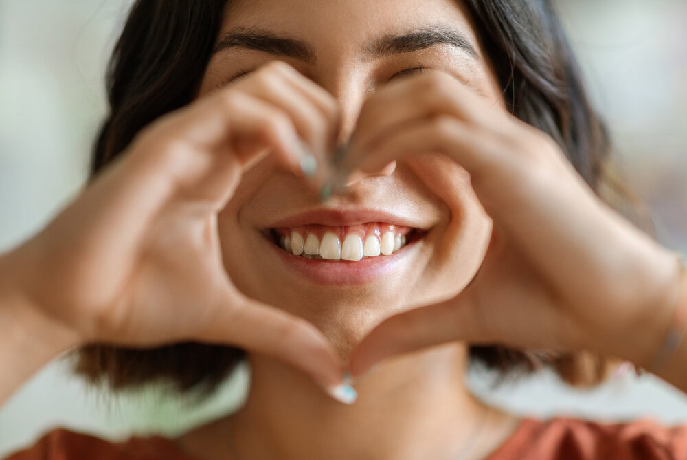 Woman smiling and making a heart shape with her hands