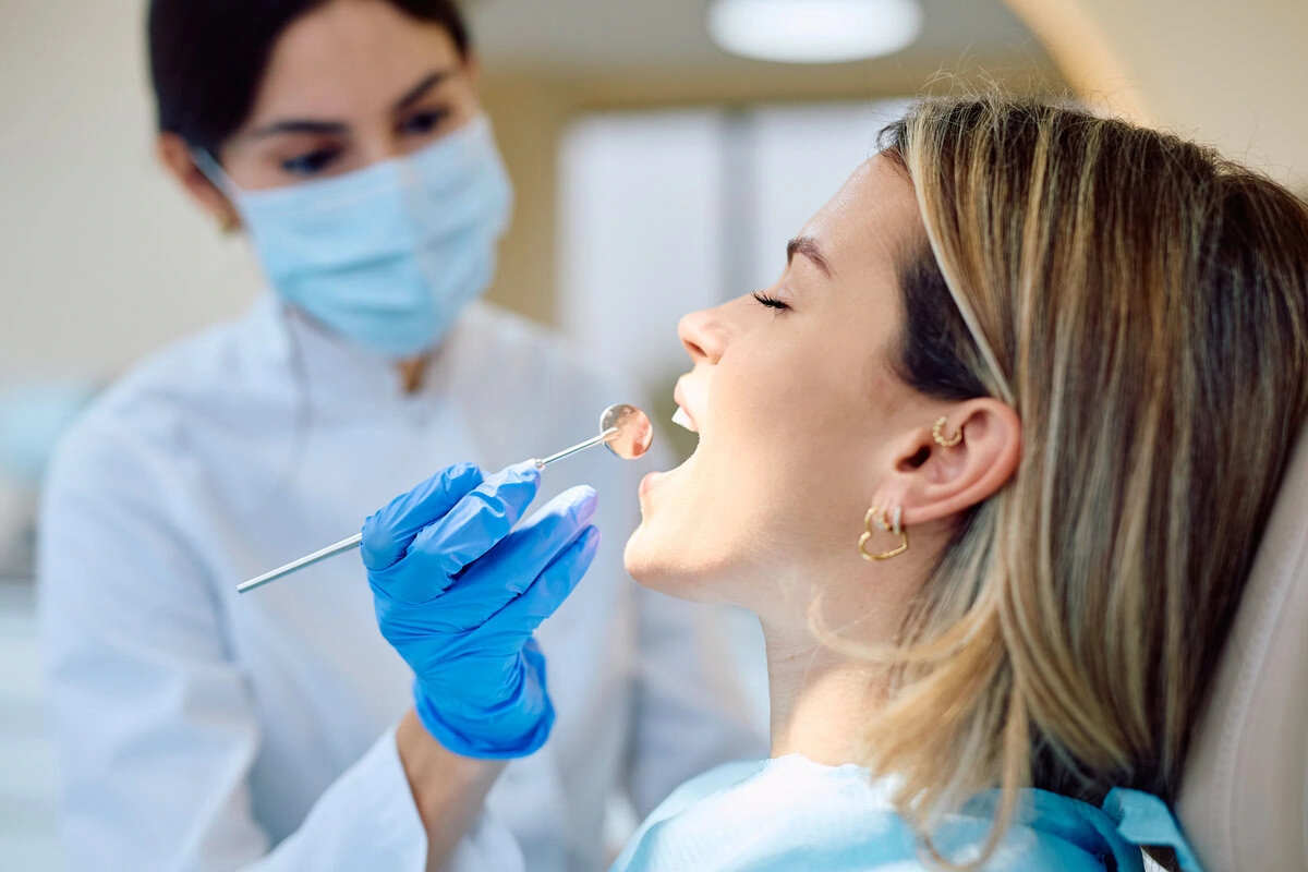 Masked dentist treating a reclined patient