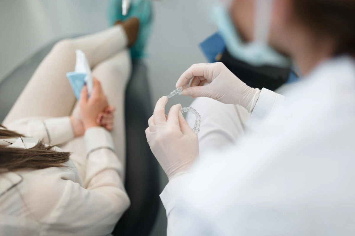 Dentist holding a clear aligner tray during a treatment visit