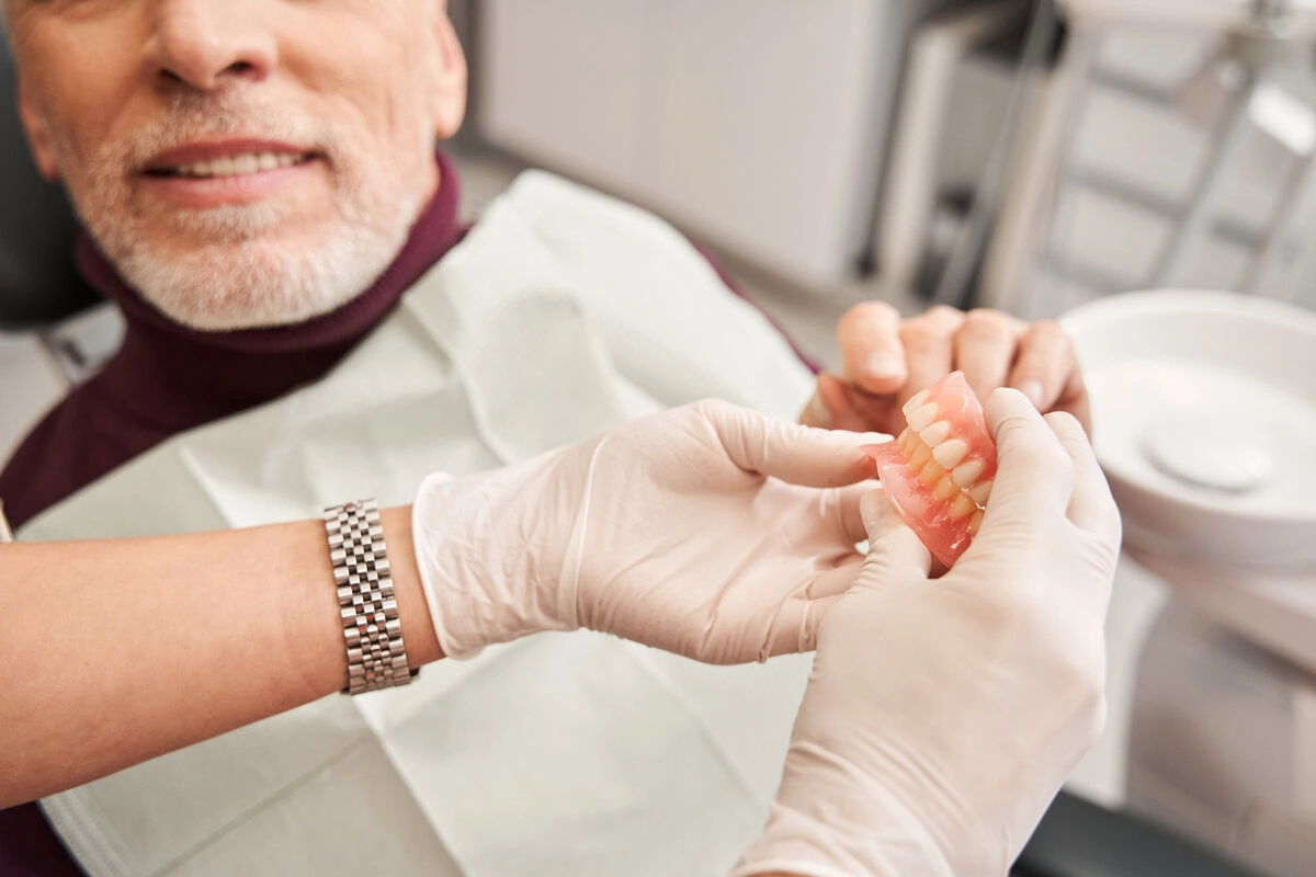 Dental team member fitting dentures for an older patient