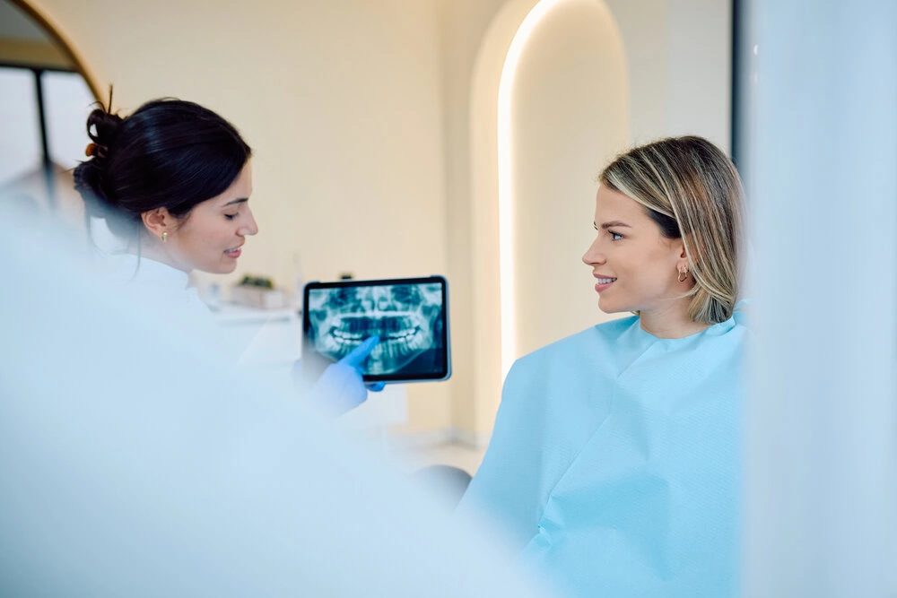 Dentist reviewing a dental X-ray on a tablet with a patient