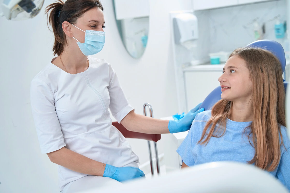 Dentist talking with a young patient during her appointment