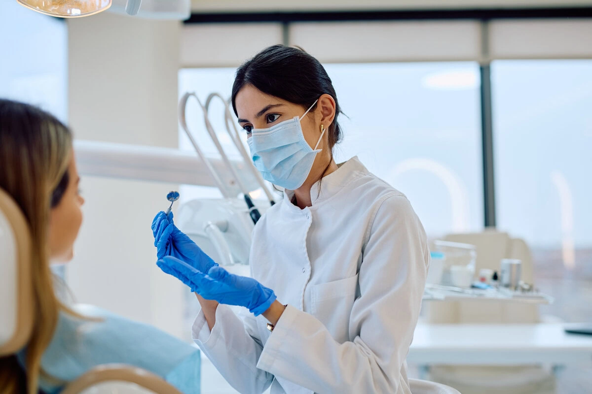 Dentist in mask and gloves preparing to treat a patient