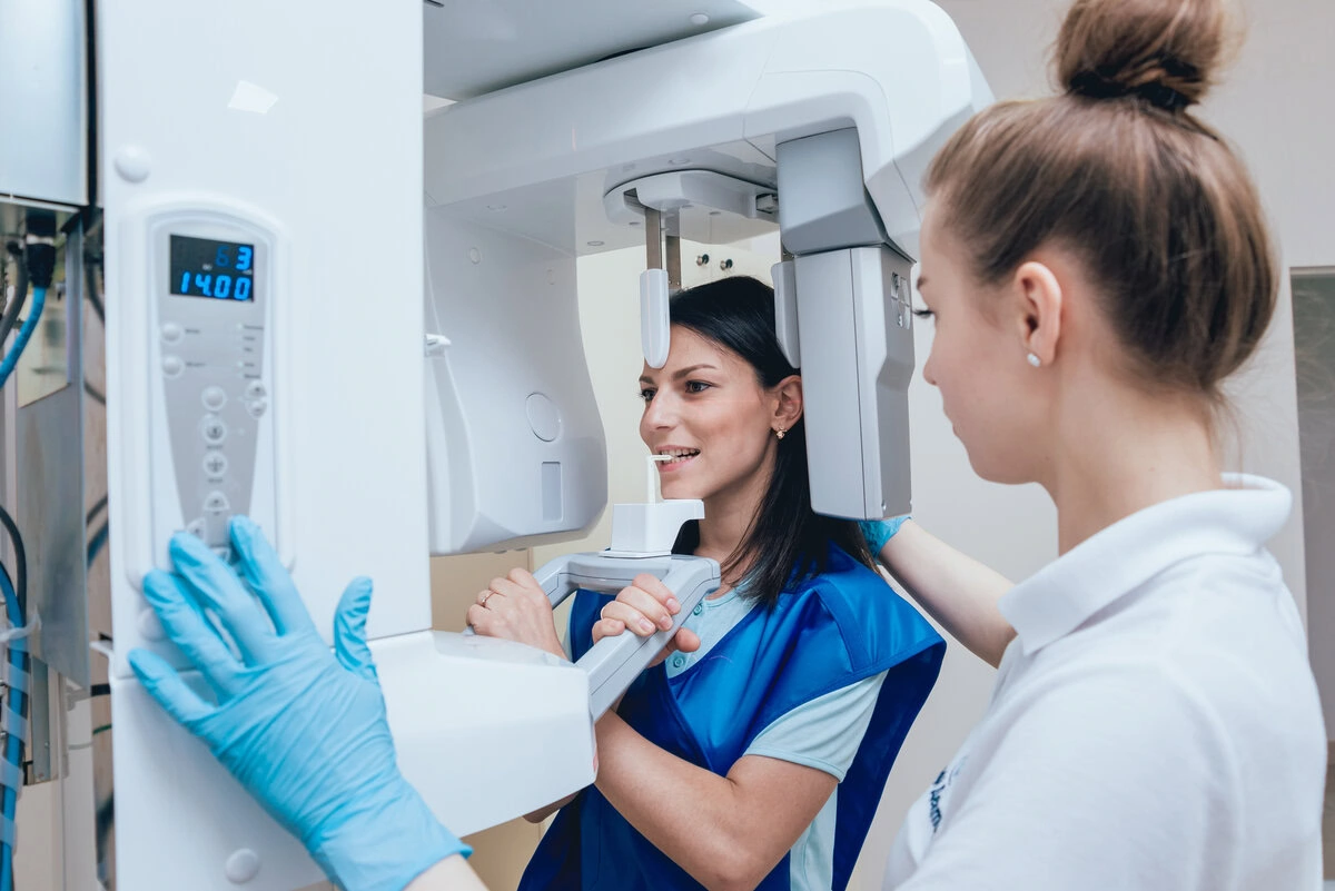 Dental team member positioning X-ray equipment for a patient